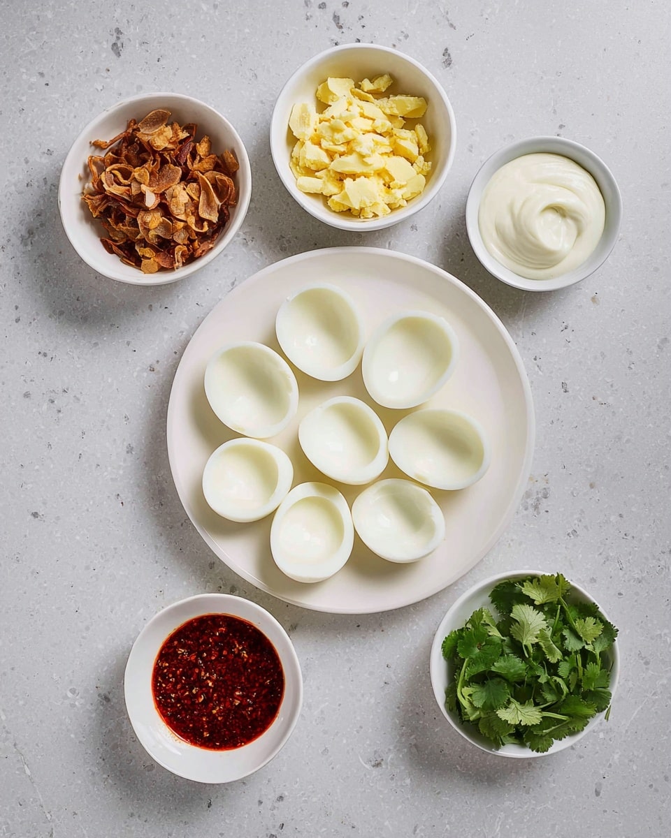 A white round plate at the bottom holds about fifteen empty egg white halves arranged neatly in two layers, showing smooth and clean inner surfaces. Above the plate, there is a white bowl filled with roughly chopped yellow egg yolks in two layers. Surrounding this bowl are four smaller white bowls: the top right bowl contains creamy white mayo with a smooth texture, the bottom right bowl has fresh green cilantro leaves with a leafy texture, the bottom left bowl holds a red spicy seasoning sauce with a slightly oily surface, and the top left bowl contains crispy brown fried onions with a crunchy texture. All items are placed on a white marbled surface. Photo taken with an iphone --ar 4:5 --v 7
