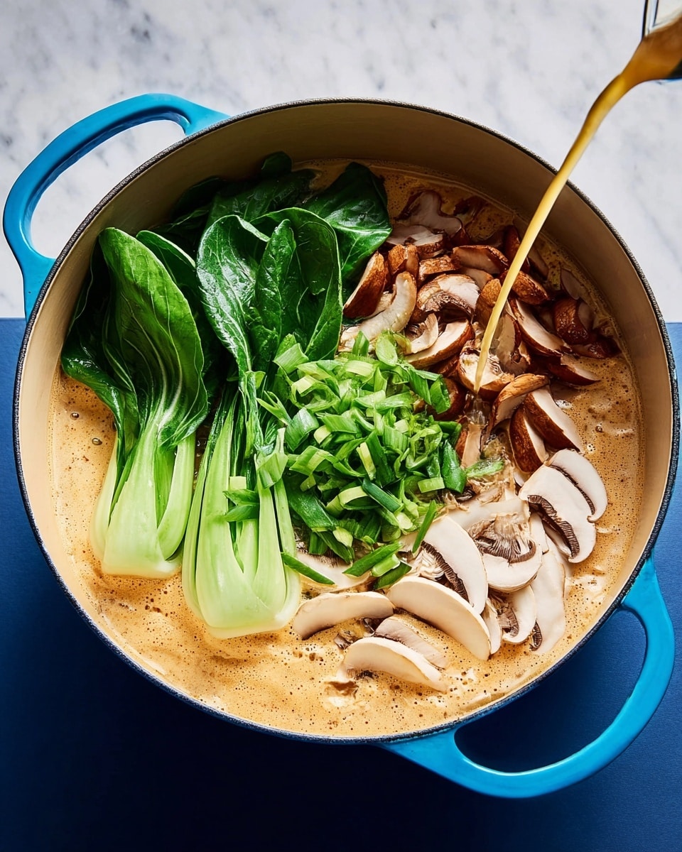 A round pot with light beige inside and bright blue handles holds a layered dish. The bottom layer is a creamy light brown soup with a smooth texture, filling half the pot. On top, several fresh green leafy bok choy pieces sit on the left side, showing their thick stems and dark green leaves. Right next to the greens on the right side is a layer of sliced brown mushrooms with white edges, neatly spread out. In the center lies a small pile of finely sliced green onions with a fresh, bright green color. A clear golden liquid is being poured into the pot from the bottom, adding shine and movement to the scene. The pot rests on a plain white marbled surface. Photo taken with an iphone --ar 4:5 --v 7