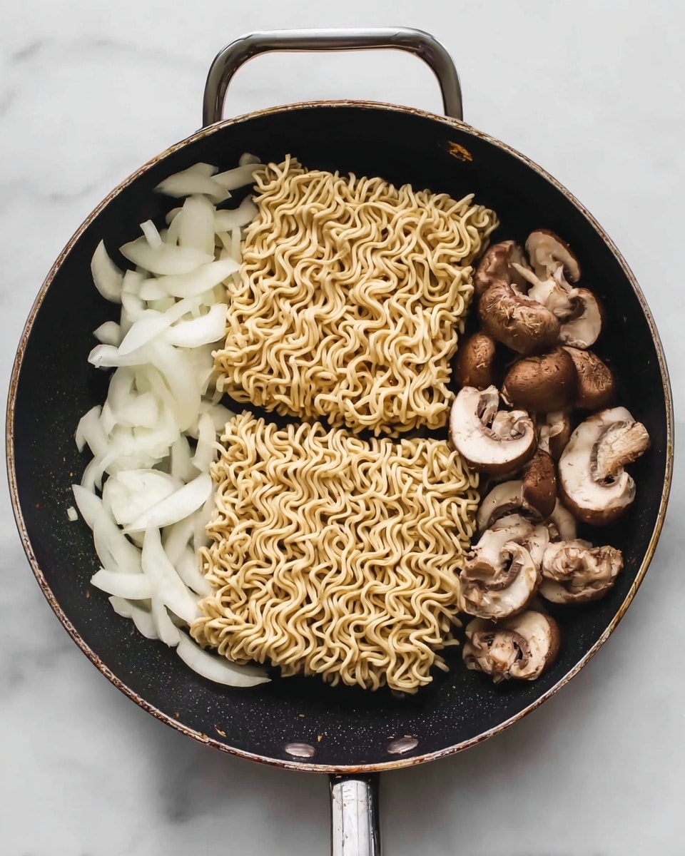 In a black frying pan on a white marbled surface, there are two blocks of square dry noodles side by side near the center. To the right of the noodles, there is a neat row of halved and whole brown and white mushrooms with a smooth texture. On the left side, there are white onion pieces cut into strips and placed in a small pile. The pan handle points upwards, and the lighting shows the texture of the noodles and vegetables clearly, photo taken with an iphone --ar 4:5 --v 7