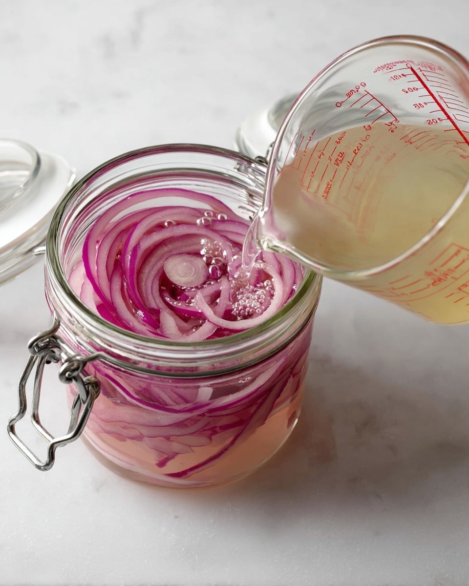 A clear glass jar with a metal latch is filled with thin, circular rings of red onion submerged in a pale pink liquid with small bubbles on the surface. To the right of the jar, a glass measuring cup marked with red measurement lines is tilted, pouring a light yellow liquid into the jar. The scene is set on a white marbled surface, with the jar lid open and resting nearby. photo taken with an iphone --ar 4:5 --v 7