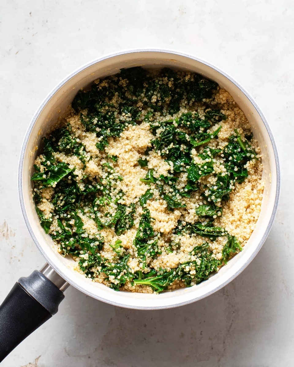 A white saucepan filled with two main layers: pale, fluffy quinoa with a slightly grainy texture, mixed evenly with dark green, curly kale leaves that appear tender and slightly wilted, giving a fresh and healthy look. The quinoa and kale are spread throughout the pot, creating a balanced mix of light beige and deep green colors. The handle of the saucepan is black and positioned on the left side. The background is a white marbled texture. photo taken with an iphone --ar 4:5 --v 7