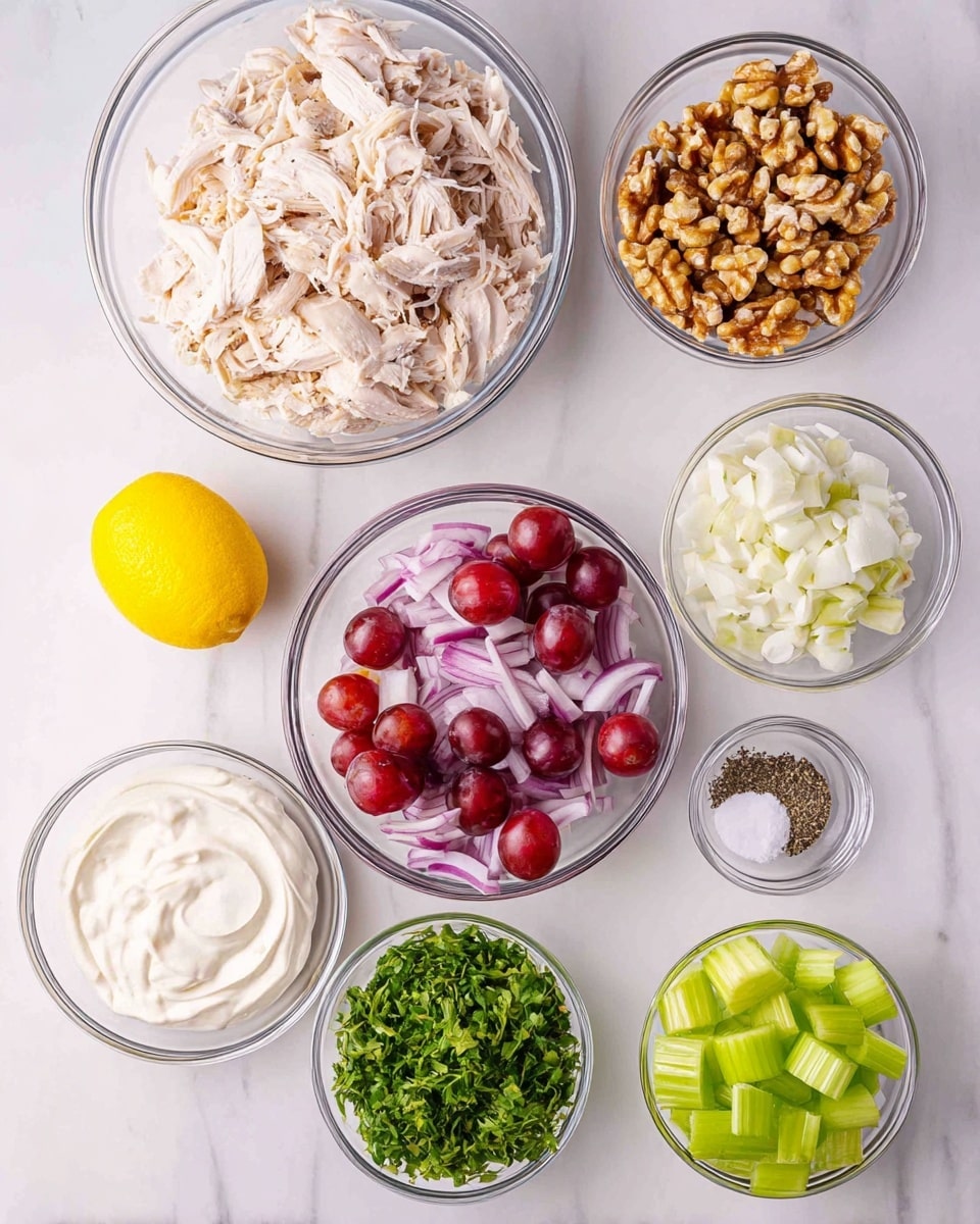 The image shows several clear glass bowls arranged on a white marbled surface. The largest bowl contains shredded white chicken meat, positioned at the top center. To the right of the chicken is a bowl of chopped light brown walnuts. Below the walnuts is a bowl filled with white creamy mayonnaise or a similar sauce. To the left of that sauce is a medium-sized bowl of red grapes, some sliced in half showing their pale interiors. Above the grapes is a bowl of diced purple-red onion. To the left of the onion is a bowl of bright green celery slices. Below the celery is a small bowl filled with finely chopped green herbs. At the bottom left corner of the image is a whole yellow lemon. Next to the lemon are two small bowls containing salt and cracked black pepper. Everything is neat and clean, and the colors stand out against the white marbled background. Photo taken with an iphone --ar 4:5 --v 7