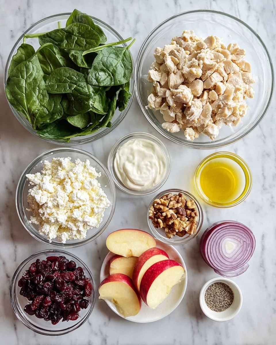 The image shows several clear glass bowls arranged on a white marbled surface, each containing different ingredients. There is a large bowl filled with small, light beige chopped pieces that look like chicken, and another large bowl with fresh, dark green spinach leaves. A medium bowl holds a white creamy substance, while another has cottage cheese. Smaller bowls contain dark red dried cranberries, brown chopped nuts, and a tiny amount of golden oil. On the side, a few red apple slices and a wedge of red onion sit directly on the surface, along with a whole yellow lemon and a small white bowl with a mix of black pepper and garlic powder. photo taken with an iphone --ar 4:5 --v 7