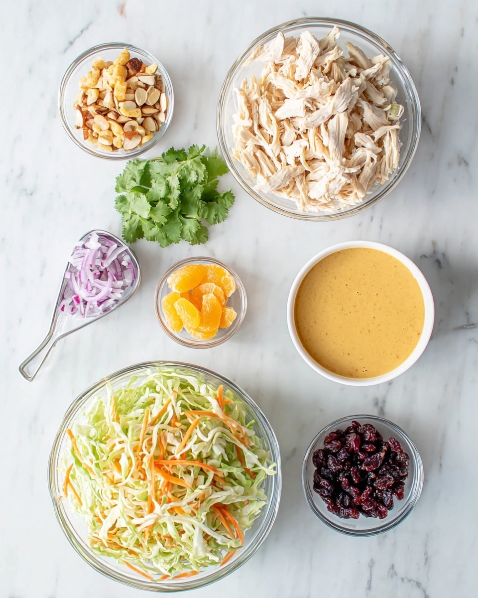 A flat lay image showing the ingredients for a salad on a white marbled surface. At the bottom center is a clear glass bowl filled with shredded green and white cabbage and thin orange carrot strips. Above it at the top right is a larger clear glass bowl with shredded light beige cooked chicken. To the right of the chicken bowl is a small white bowl filled with mixed sliced almonds and other nuts. Just left of the nut bowl is a sprig of fresh cilantro. In the center is a small clear glass bowl holding a creamy orange dressing. To the left of the dressing are three tiny clear bowls arranged vertically: the top bowl has small golden brown crunchy pieces, the middle one contains small pale orange segments, and the bottom holds dark red dried cranberries. To the far left and slightly down is a small white measuring cup with finely chopped purple onions. The photo taken with an iphone --ar 4:5 --v 7