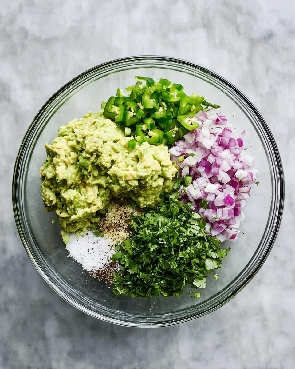 A clear glass bowl sits on a white marbled surface, filled with six distinct layers of ingredients ready to be mixed. In the bottom left is a creamy light green mashed avocado with a slightly chunky texture. Next to it on the right is a pile of small, bright green diced jalapeño peppers. Above the jalapeños are finely chopped red onions, showing a mix of white and deep pink colors. Beside the onions is a heap of chopped fresh cilantro leaves, rich green and leafy. Between the cilantro and avocado lies a small mound of white granulated salt. Lastly, near the salt is a patch of crushed black pepper with a coarse texture and finely chopped pale yellow garlic pieces. photo taken with an iphone --ar 4:5 --v 7