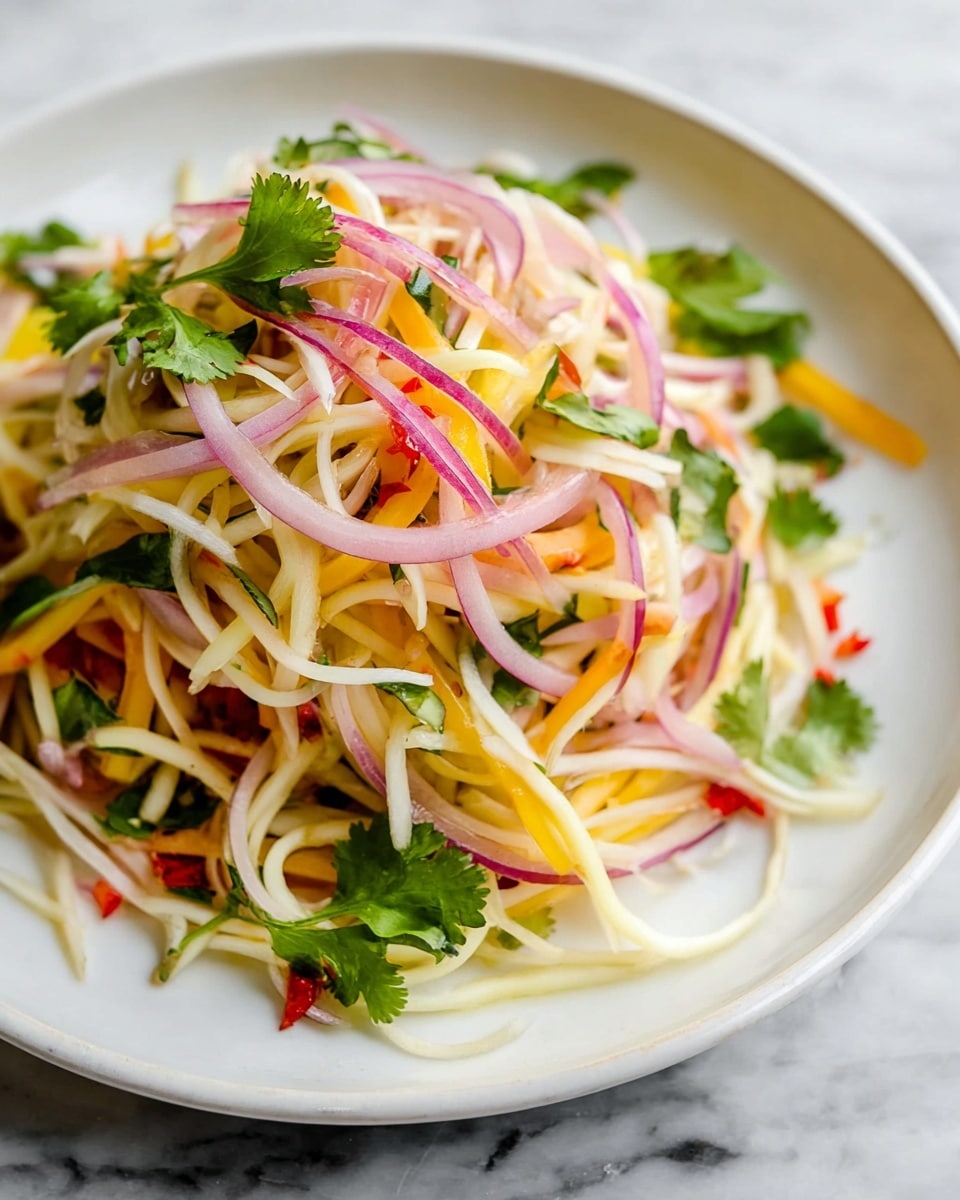 A white plate holds a colorful salad arranged in loose layers. The base layer is made of thin, long white strips resembling julienned vegetables, mixed with thin pale yellow and orange strips. On top of this are thin slices of purple-red onions spread evenly, adding a translucent texture. Bright green cilantro leaves are scattered throughout and on top, giving bursts of fresh color. Bits of red pieces are mixed in, adding small pops of contrasting color. The plate sits on a white marbled surface. photo taken with an iphone --ar 4:5 --v 7
