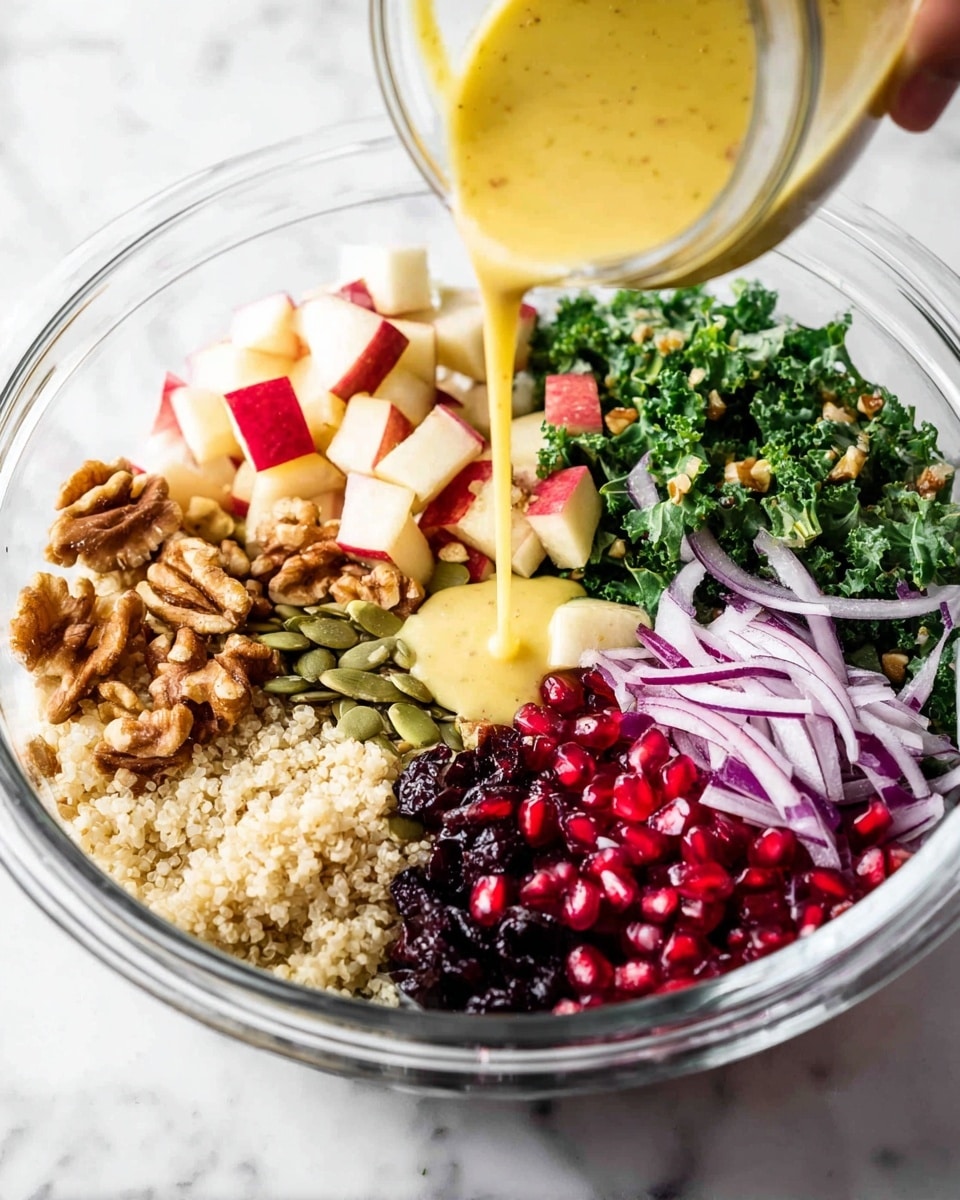 A clear glass bowl on a white marbled surface contains a colorful salad with seven layers arranged in separate sections: at the bottom center is a light beige grain layer with a soft, fluffy texture; to the bottom left are green pumpkin seeds; above them to the left is chopped green leafy kale; at the top left, small cubes of red apple with white flesh; next to the apple, large brown walnut pieces; to the right of the walnuts, thin purple and white rings of red onion; below the onion are bright red pomegranate seeds; and next to the pomegranate seeds, in the middle, dark dried cherries or cranberries. A woman's hand is pouring a yellow, creamy dressing over the salad from a clear jar. Photo taken with an iphone --ar 4:5 --v 7