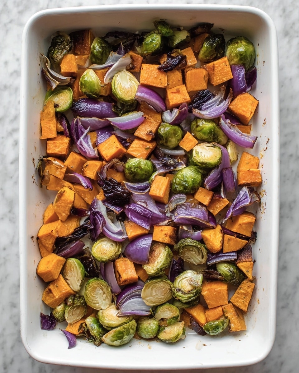 The image shows a white rectangular baking dish filled with one layer of roasted vegetables. There are chunky orange pieces of sweet potato scattered evenly, alongside green halved Brussels sprouts with some charred edges. Roughly chopped purple onion pieces add a pop of color, some with dark, crisp edges from roasting. The vegetables have a mix of soft and crispy textures with slight browning. The baking dish is placed on a white marbled surface. photo taken with an iphone --ar 4:5 --v 7