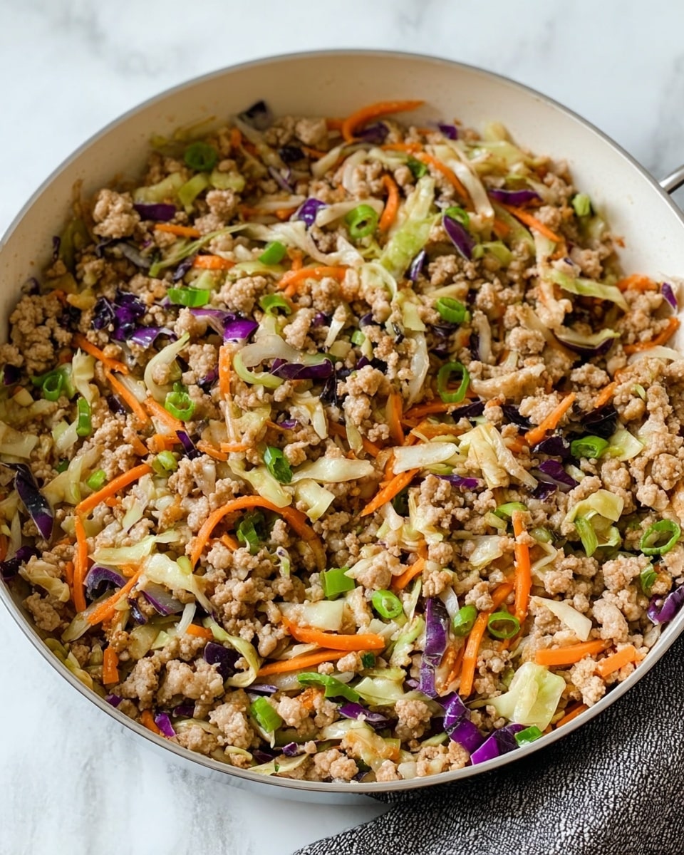 The image shows a white pan filled with cooked ground meat mixed with small pieces of shredded vegetables. There are layers of light brown meat scattered throughout, with thin orange carrot sticks, small bits of green onions, and pieces of purple and light green cabbage mixed evenly in the dish. The texture looks soft with the vegetables adding slight crunch, and the pan is placed on a surface with a white marbled texture. photo taken with an iphone --ar 4:5 --v 7