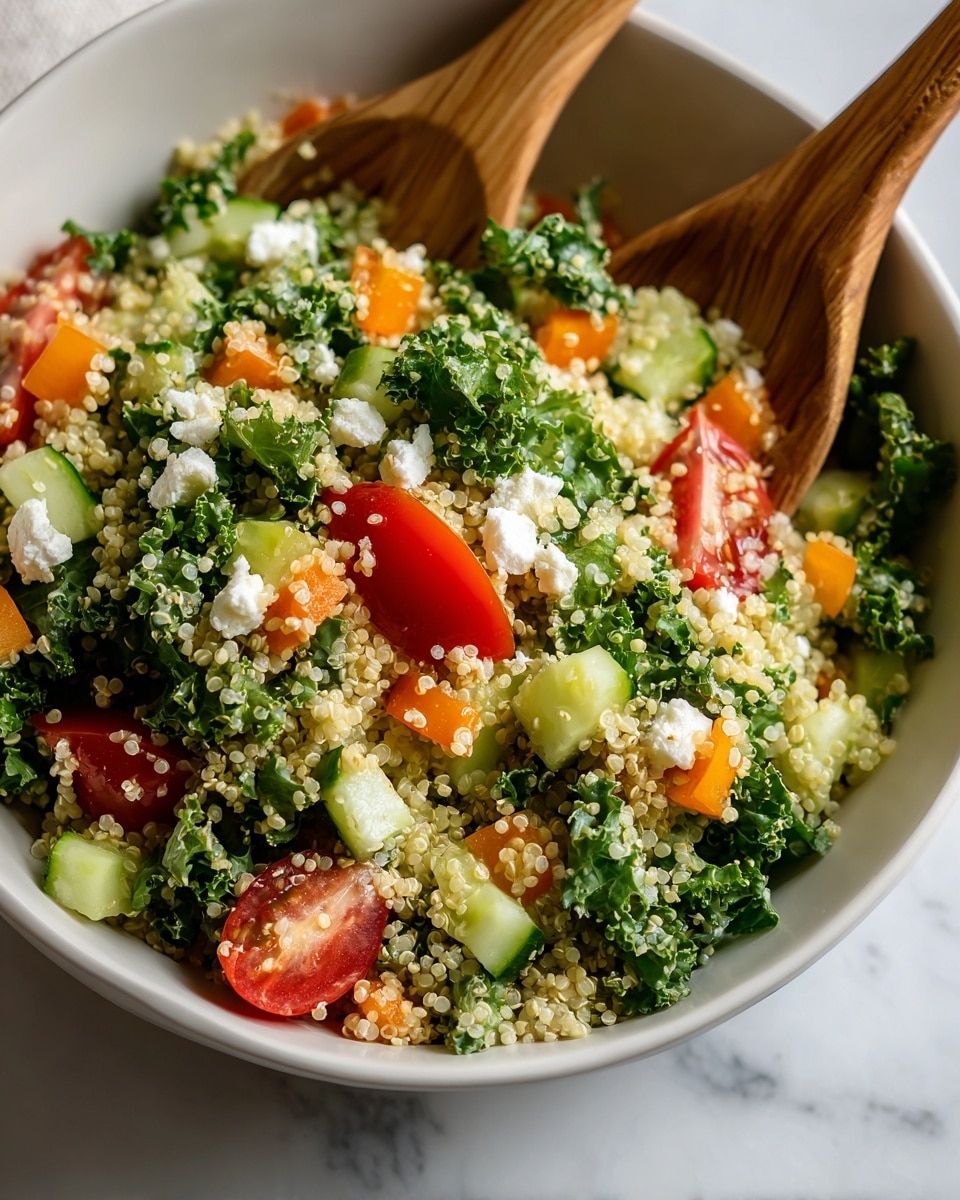 The image shows a close-up view of a colorful salad in a white bowl. The salad has several layers: at the bottom, small round quinoa grains form a light beige base with a soft texture. Above this, there are bright green pieces of curly kale leaves with a rough texture, mixed with small diced orange bell peppers and chopped light green cucumber cubes. Scattered throughout the salad are halves of shiny red grape tomatoes and small chunks of white crumbly cheese. Two wooden salad spoons are partially inserted into the salad, adding a natural brown color contrast. The whole scene rests on a white marbled surface, making the colors of the salad stand out vividly. Photo taken with an iphone --ar 4:5 --v 7