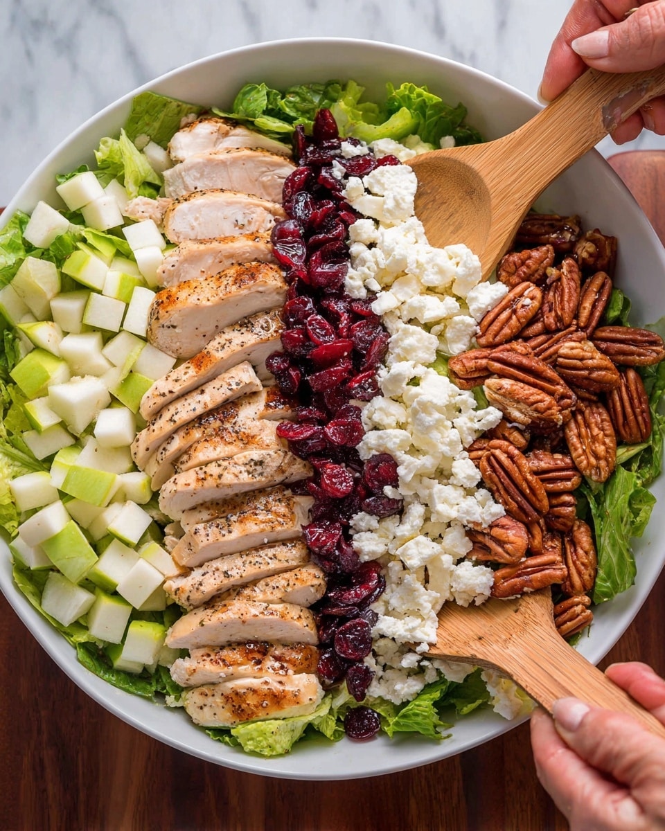 A white bowl filled with a salad made in six layers, all neatly arranged side by side. The bottom layer is made of green leafy lettuce, covering the entire bowl. On the left is a layer of small light green and white diced pear pieces, next to that is sliced grilled chicken with light brown grill marks and some black pepper sprinkled on top. In the middle is a layer of dark red dried cranberries. To the right of that is a layer of white, crumbly cheese. The last layer on the far right has whole pecans that are brown and shiny. Two wooden spoons are held by a woman's hand, one on each side, slightly mixing the layers together. The bowl sits on a white marbled surface. Photo taken with an iphone --ar 4:5 --v 7