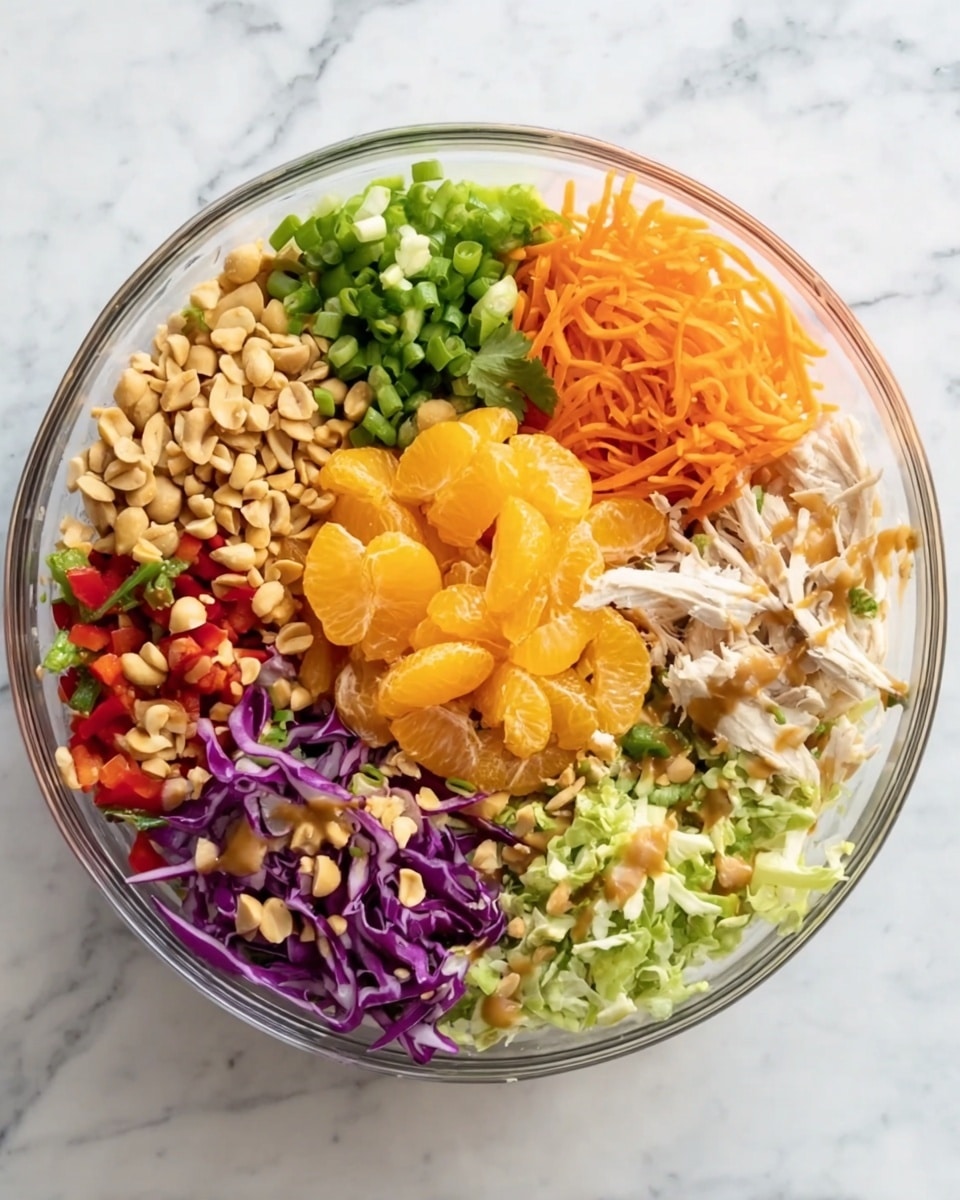 A clear glass bowl sits on a white marbled surface, filled with eight separate layers of colorful ingredients arranged in sections. Starting from the top left moving clockwise, there are chopped green onions with a green and white texture, shredded light brown almonds, thin orange shredded carrots, shredded purple and white cabbage, chopped green cabbage mixed with purple cabbage, small diced bright red bell peppers, fresh green cilantro leaves, roasted light brown peanuts, shredded white chicken meat, and a bright orange pile of mandarin slices in the center. All the layers have light brown dressing drizzled over them. Photo taken with an iphone --ar 4:5 --v 7