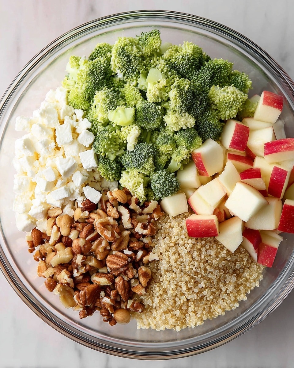 A clear glass bowl filled with five distinct layers arranged side by side. Starting from the top left, there is a mound of light green broccoli florets with a slightly rough texture. Below the broccoli, a flaky white layer of cottage cheese is placed. To the bottom right, small cubes of red-skinned apple add a mix of red and off-white colors. Next to the apple cubes on the left, there is a chunky pile of mixed nuts, including walnuts and almonds, showing various shades of brown with rough textures. The last layer, filling the bottom left, consists of light tan cooked quinoa grains, fine and slightly fluffy. The bowl sits on a white marbled surface photo taken with an iphone --ar 4:5 --v 7