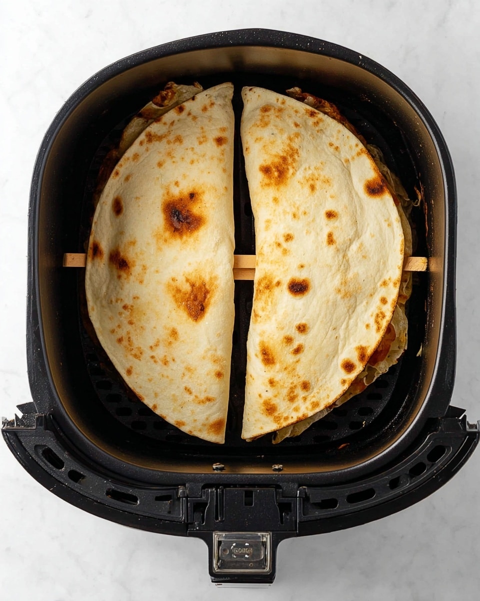 Inside a black air fryer basket, there are two folded flatbreads placed side by side, each secured with small wooden toothpicks. The flatbreads have a light golden color with slightly darker brown spots, showing a toasted texture. The edges of the flatbreads curve gently, hinting at a soft inside. The air fryer basket is well-ventilated with small round holes on the sides. The whole scene is set against a white marbled surface. photo taken with an iphone --ar 4:5 --v 7