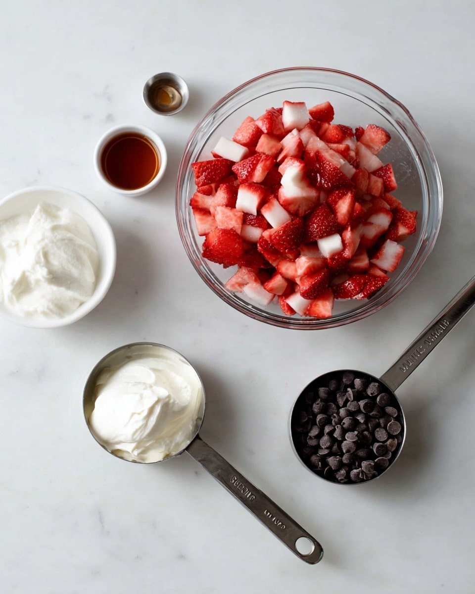 The image shows a white marbled surface with a neat arrangement of ingredients. In the center is a clear glass bowl filled with small pieces of red and white chopped strawberries that have a fresh and juicy texture. To the front and slightly right is a metal measuring cup filled with small dark chocolate chips. To the left, there is a metal measuring cup filled with smooth, white cream, with a metal handle resting on the surface. Behind the strawberries is a white bowl holding a small amount of white solid coconut oil. Two metal measuring spoons are also present: one filled with dark amber liquid, placed near the bottom left, and another spoon filled with a darker liquid placed near the top right. The overall scene looks clean and ready for mixing ingredients photo taken with an iphone --ar 4:5 --v 7