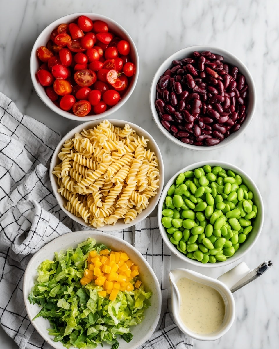 A top view of several white bowls on a white marbled surface, each bowl holding a different colorful ingredient: bright red cherry tomatoes, dark red kidney beans, pale yellow chickpea pasta shaped like spirals, vibrant green edamame, light green chopped lettuce in a bowl placed on a white cloth with black grid lines, and diced yellow bell pepper. Next to the bowls is a small white pitcher filled with creamy Italian dressing. The colors contrast well against the clean white background photo taken with an iphone --ar 4:5 --v 7