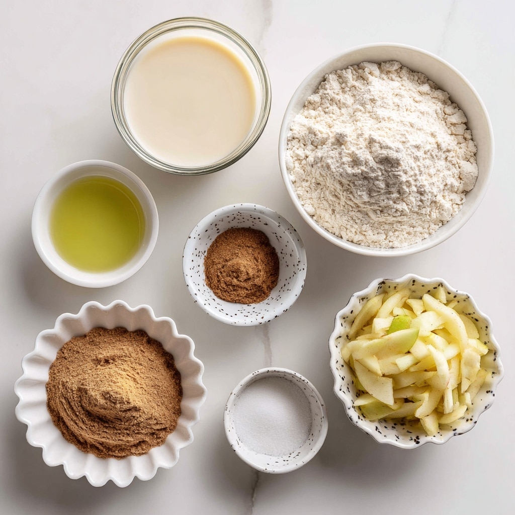 The image shows several small white bowls and a glass container arranged neatly on a white marbled surface. At the top center, there is a clear glass container filled with a creamy liquid labeled dairy-free milk. Below and to the left is a small white bowl with light green oil. To the right of the oil, a larger white bowl holds a heap of white flour with a fine, powdery texture. Below the oil, there is a white fluted bowl filled with medium brown sugar that looks soft and slightly moist. Next to the brown sugar bowl, a small, scalloped white dish contains pure white baking powder and soda. To the right, a small white bowl with a black dot pattern is filled with shredded apple pieces, light yellow in color with hints of brown. Nearby, a tiny white bowl holds a pale yellow liquid labeled apple cider vinegar (optional). Finally, at the bottom left, a shallow white bowl contains a mixture of brown cinnamon and a touch of salt. photo taken with an iphone --ar 4:5 --v 7