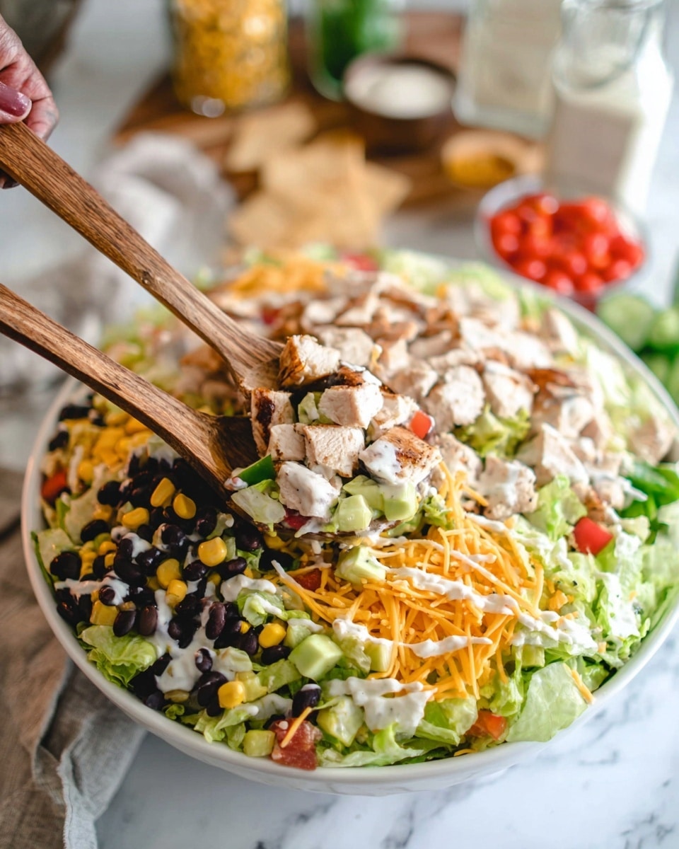 A large white bowl filled with a colorful layered salad, beginning with a base of chopped light green lettuce. On top are scattered black beans, bright yellow corn kernels, and small diced red tomatoes. There are chunks of cooked light brown chicken mixed throughout, along with shredded orange cheese and slices of pale green cucumber. The salad has a creamy white dressing drizzled over it. Two wooden serving spoons are scooping a portion, held by a woman's hand in the background. The setting is on a white marbled surface with blurred ingredients and kitchen items in the background. Photo taken with an iphone --ar 4:5 --v 7