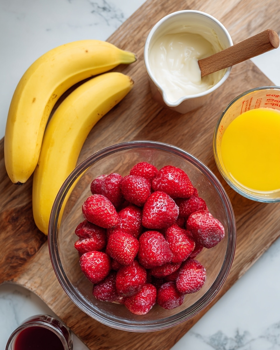 A clear glass bowl filled with many bright red frozen strawberries is in the center, resting on a wooden surface. To the left of the bowl, there are two yellow bananas lying next to each other, and near the bottom, there is a small glass container with a dark liquid. To the right of the bowl, a white saucepan with a wooden handle holds creamy white yogurt or cream, and next to it is a clear glass measuring cup filled halfway with bright orange juice. The whole setting is placed on a white marbled surface photo taken with an iphone --ar 4:5 --v 7