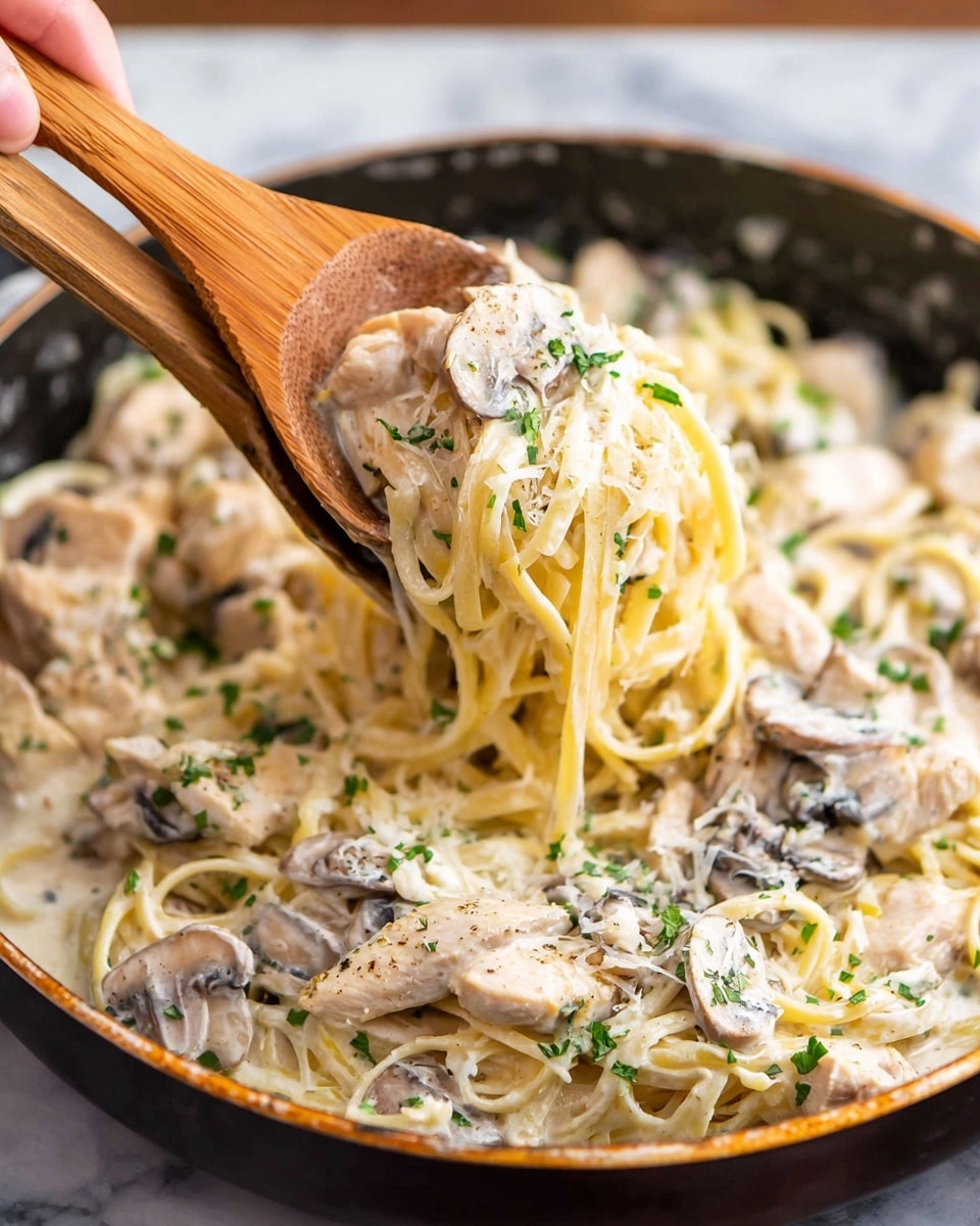 The image shows creamy pasta with three layers: the bottom layer has light yellow long pasta strands, the middle layer has soft white sauce covering the pasta, and the top layer has sliced light brown mushrooms and white chicken pieces sprinkled with green herbs. A woman's hand uses wooden spoons to lift the pasta, sauce, mushrooms, and chicken from a black pan. The background is a white marbled surface. photo taken with an iphone --ar 4:5 --v 7