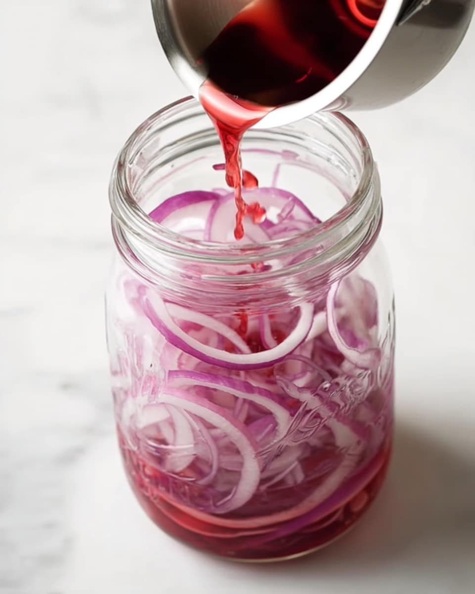 Thin slices of purple and white onion fill a clear glass jar about three-quarters full, with a red liquid being poured from a small stainless steel pot above it. The jar is on a white marbled surface, and the red liquid creates small splashes as it hits the onions. The scene is bright and clear, focusing closely on the jar and the pouring action. Photo taken with an iphone --ar 4:5 --v 7