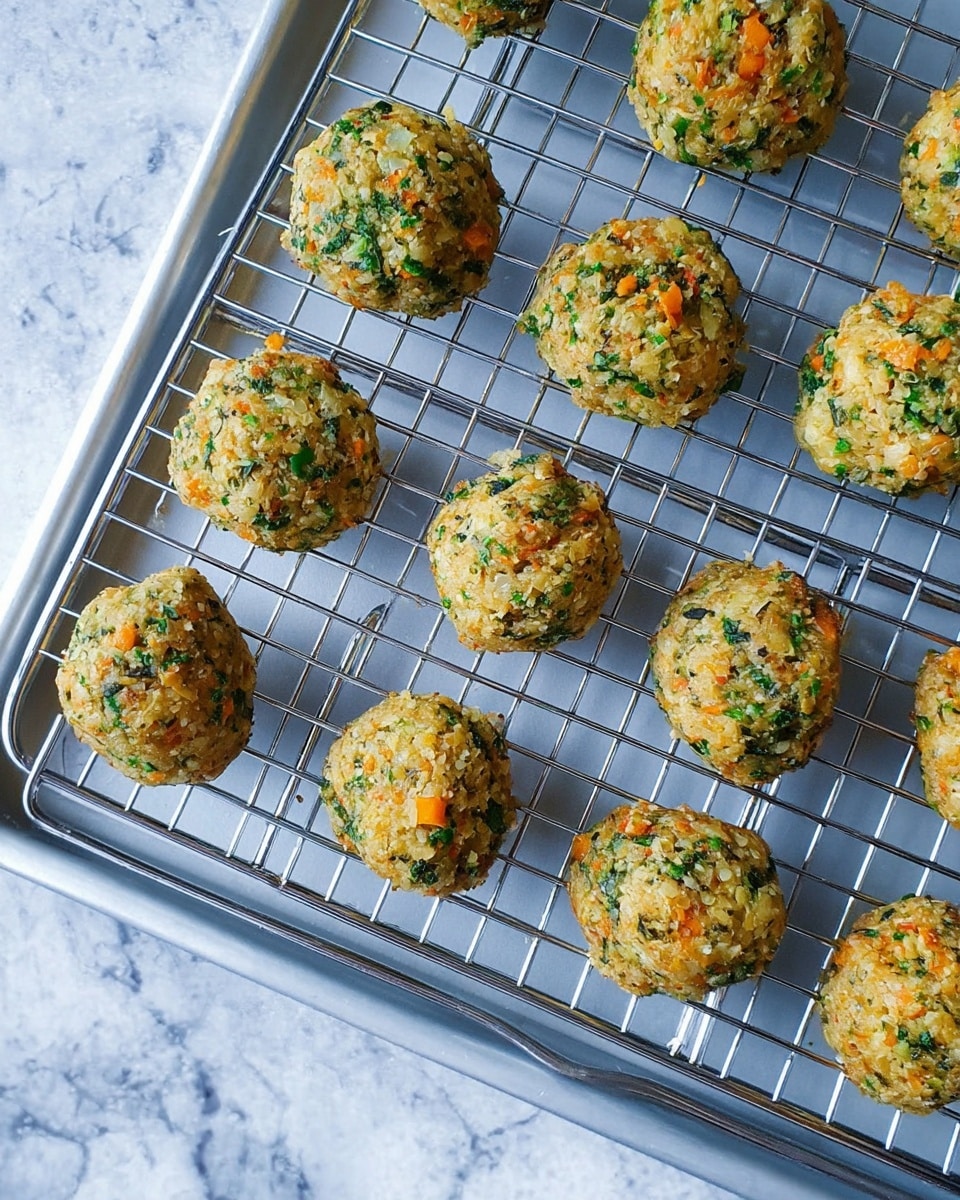 A group of small round balls made from a mixture of ingredients including visible bits of green vegetables and orange flecks, placed evenly on a silver metal cooling rack that sits on a white tray. The background is a white marbled texture. The balls have a slightly rough texture and vary slightly in size. Photo taken with an iphone --ar 4:5 --v 7