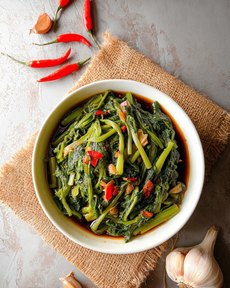 A white bowl filled with cooked green water spinach stems and leaves mixed with small pieces of garlic and sliced red chili peppers spread on top, soaking in a dark soy-based sauce at the bottom. The bowl rests on a square piece of coarse brown burlap fabric on a white marbled surface. Around the bowl, there are four whole red chili peppers and two garlic cloves, with one clove still in its bulb form. Photo taken with an iphone --ar 4:5 --v 7