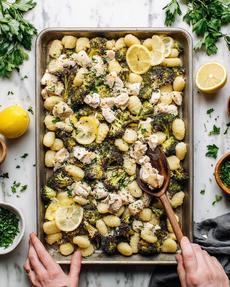 A large metal tray holds a dish with three main layers: the bottom layer is potato gnocchi, soft and pale yellow with a light bumpy texture, spread all over the tray; the second layer is roasted broccoli florets, dark green with some browned edges, mixed evenly throughout; the top layer consists of small chunks of white cooked chicken, scattered across the tray and sprinkled with finely chopped green herbs. Lemon slices sit on top for decoration, and grated cheese adds a hint of white on the chicken. A woman's hand holds a wooden spoon stirring the food on the right side, and another woman's hand steadies the tray from the left. The tray is on a white marbled surface with some green parsley scattered around and small bowls holding herbs and lemon slices nearby. Photo taken with an iphone --ar 4:5 --v 7
