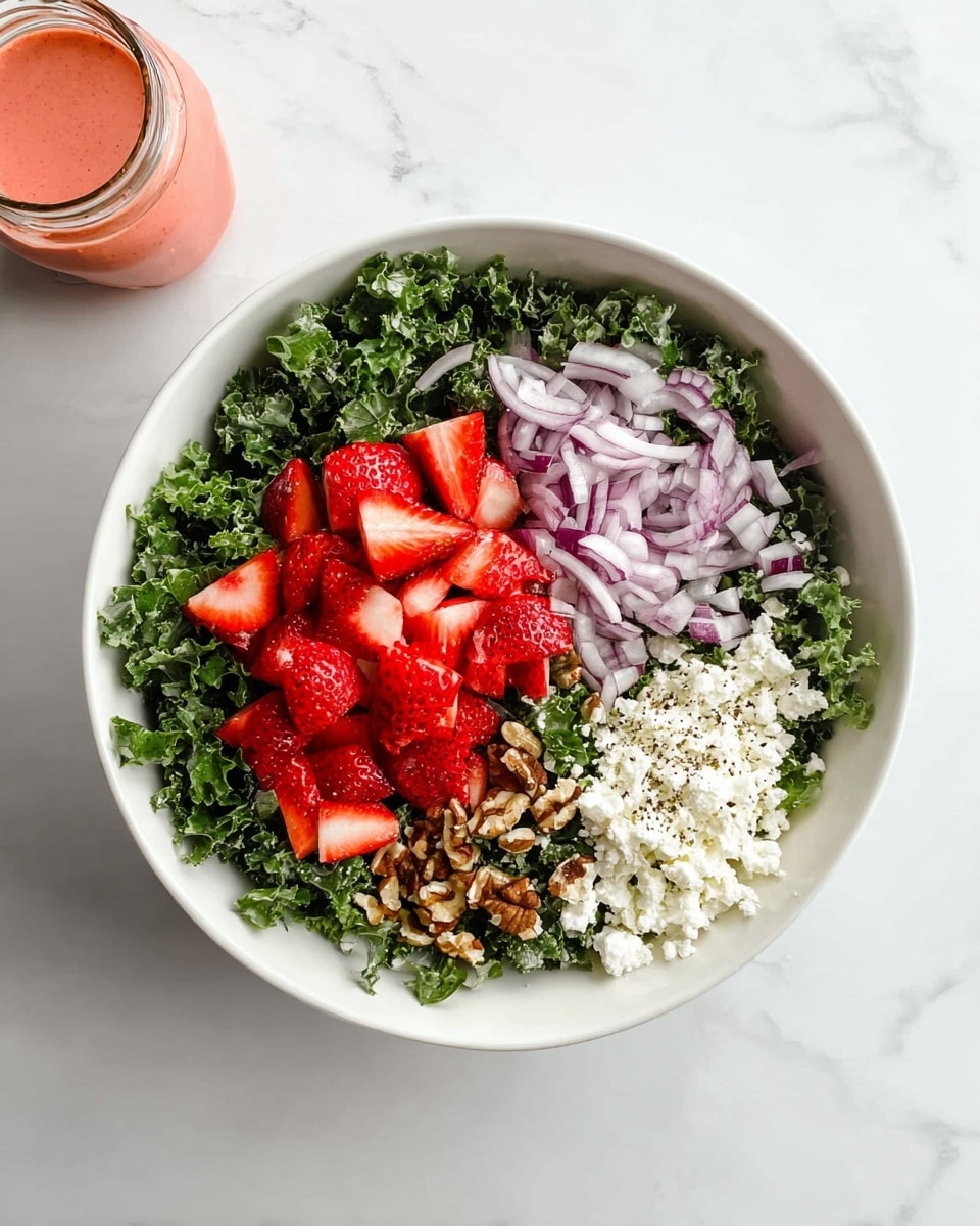 A white bowl shows five layers of salad ingredients. Around the left half, there is a large layer of dark green, leafy chopped kale. In the top center, bright red sliced strawberries form a neat cluster. To the right of the strawberries, thin, light purple-red strips of onion sit in a small pile. Below the strawberries and onions, there are small pieces of brown nuts arranged in a small pile. At the bottom right, there is a layer of soft, white crumbled cheese with a slight dusting of black pepper on top. The bowl is placed on a white marbled surface, and there is a small jar of light red dressing or sauce near the lower left corner. photo taken with an iphone --ar 4:5 --v 7