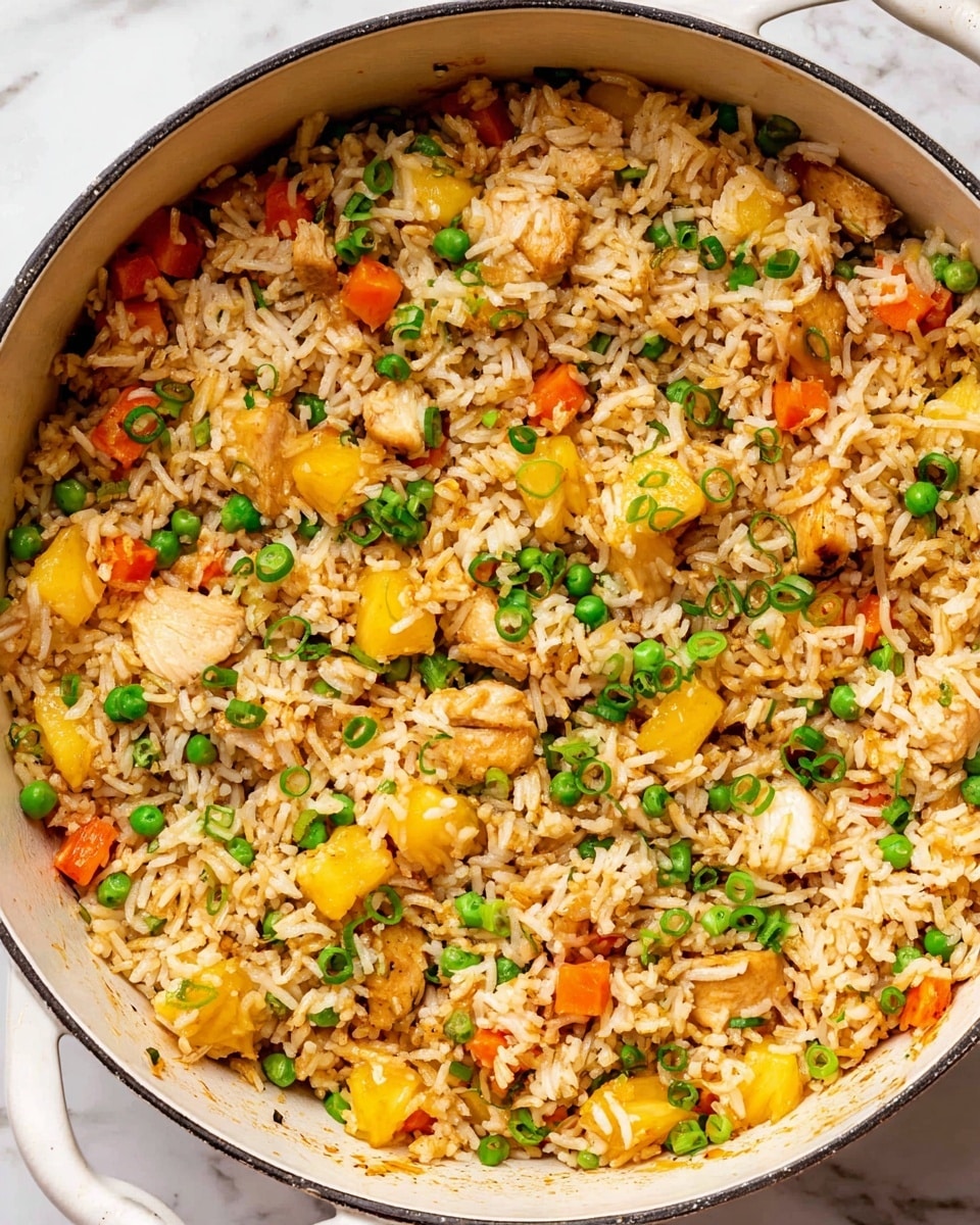 A close-up view of a large round white pot filled with mixed fried rice. The rice is light brown and has three main layers of ingredients: small white rice grains as the base, golden yellow chunks of pineapple scattered throughout, and small pieces of light brown cooked chicken. Bright green peas and small cubes of orange carrot are mixed evenly through the rice. Thin slices of fresh green onion are sprinkled on top, giving a fresh look. The pot sits on a white marbled surface. photo taken with an iphone --ar 4:5 --v 7