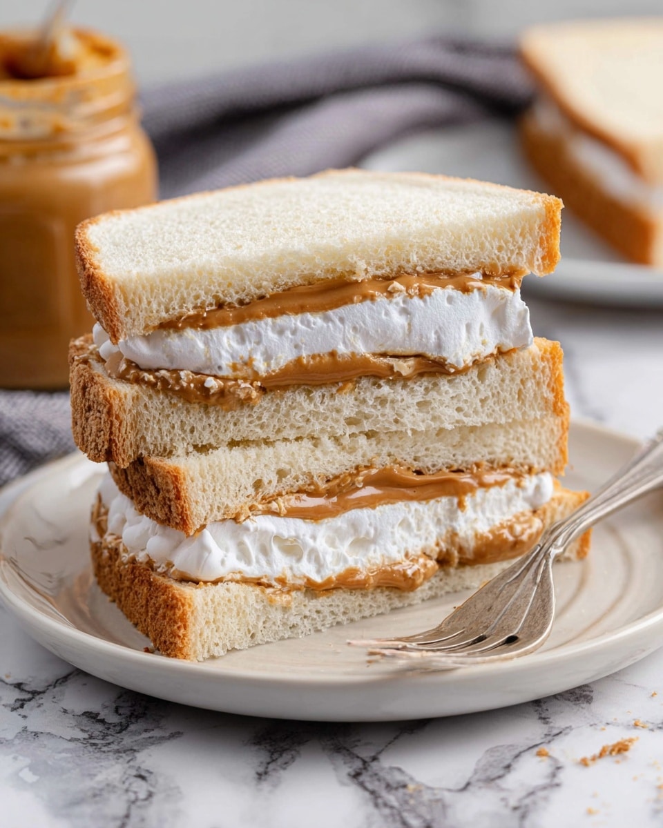 Two sandwich halves stacked on a white plate with a soft texture and light brown crust. Each sandwich has three layers: the top and bottom layers are thick slices of white bread, and between them are two layers of peanut butter and white marshmallow cream, the peanut butter layer is light brown and slightly spread out, while the marshmallow cream is thick, white, and fluffy in texture. The plate sits on a white marbled surface with a blurred jar of peanut butter and a grey cloth in the background. A silver fork lies next to the sandwiches on the plate photo taken with an iphone --ar 4:5 --v 7
