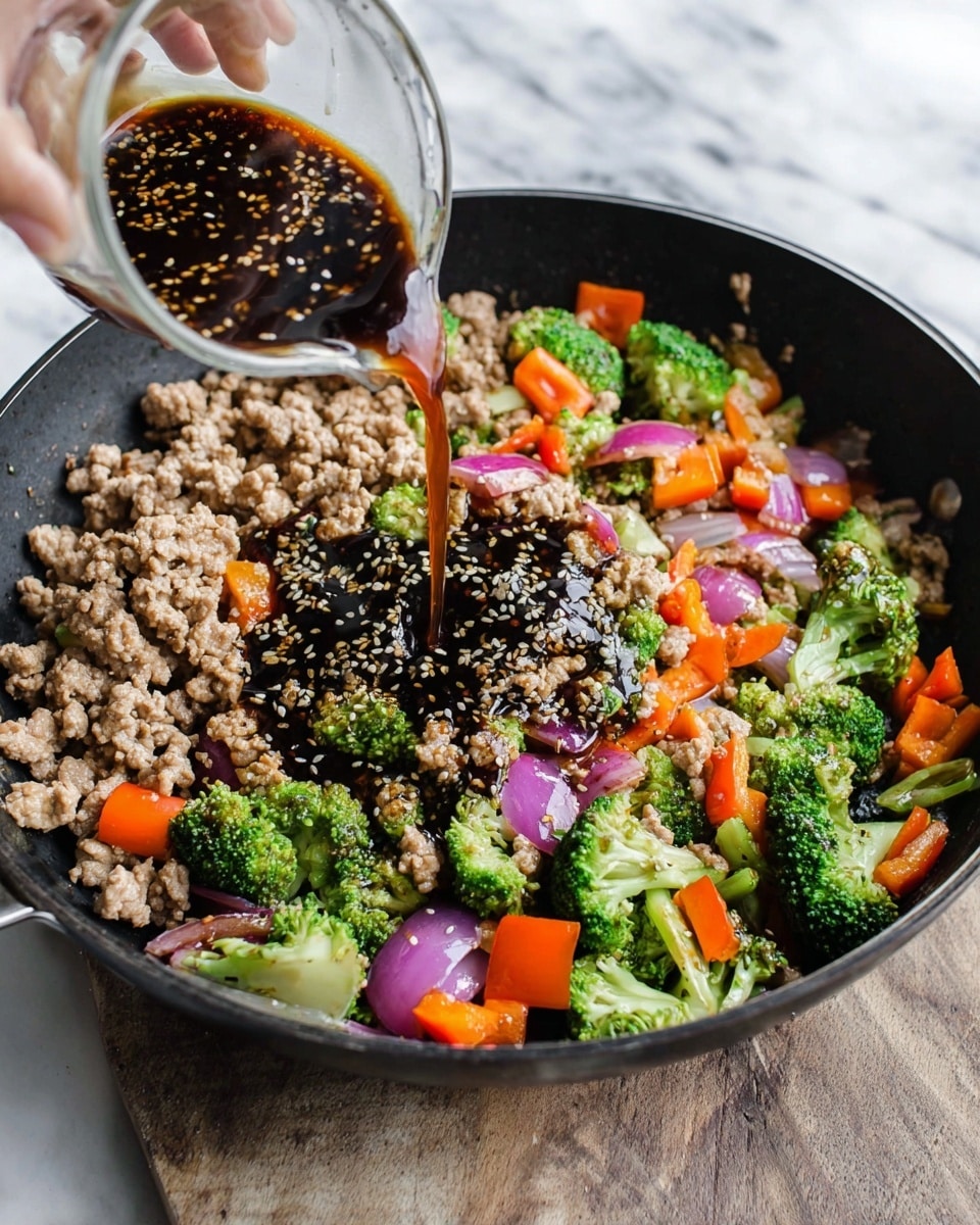 A black pan holds a colorful stir-fry with several layers. The bottom layer shows light brown cooked ground meat mixed with pieces of bright green broccoli florets, orange bell pepper chunks, and light purple onion slices. On top, dark brown sauce speckled with sesame seeds is being poured from a small measuring cup held by a woman's hand, the sauce pooling in the center and spreading over the ingredients. The pan sits on a white marbled surface. Photo taken with an iphone --ar 4:5 --v 7