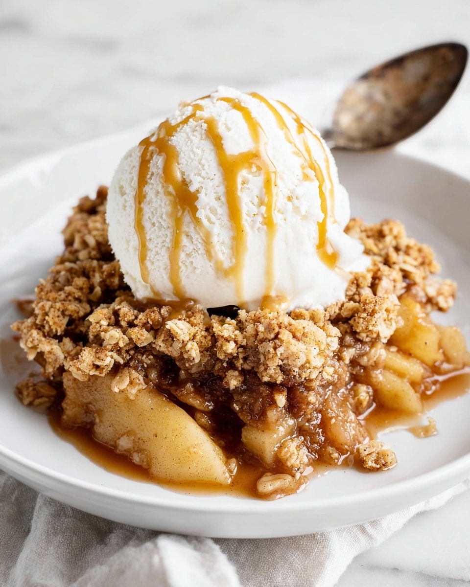The image shows a serving of apple crumble dessert on a white plate with a white marbled surface underneath. The dessert has two layers: the bottom layer is soft, cooked apple pieces in a light brown syrup, visible at the front and sides, while the top layer is a golden brown crumb mixture with a rough, grainy texture covering the apples. On top of the crumble, there is a large scoop of creamy white vanilla ice cream with visible vanilla bean specks. The ice cream is drizzled with light caramel sauce. A large, slightly old-looking spoon rests on the plate behind the dessert. Photo taken with an iphone --ar 4:5 --v 7