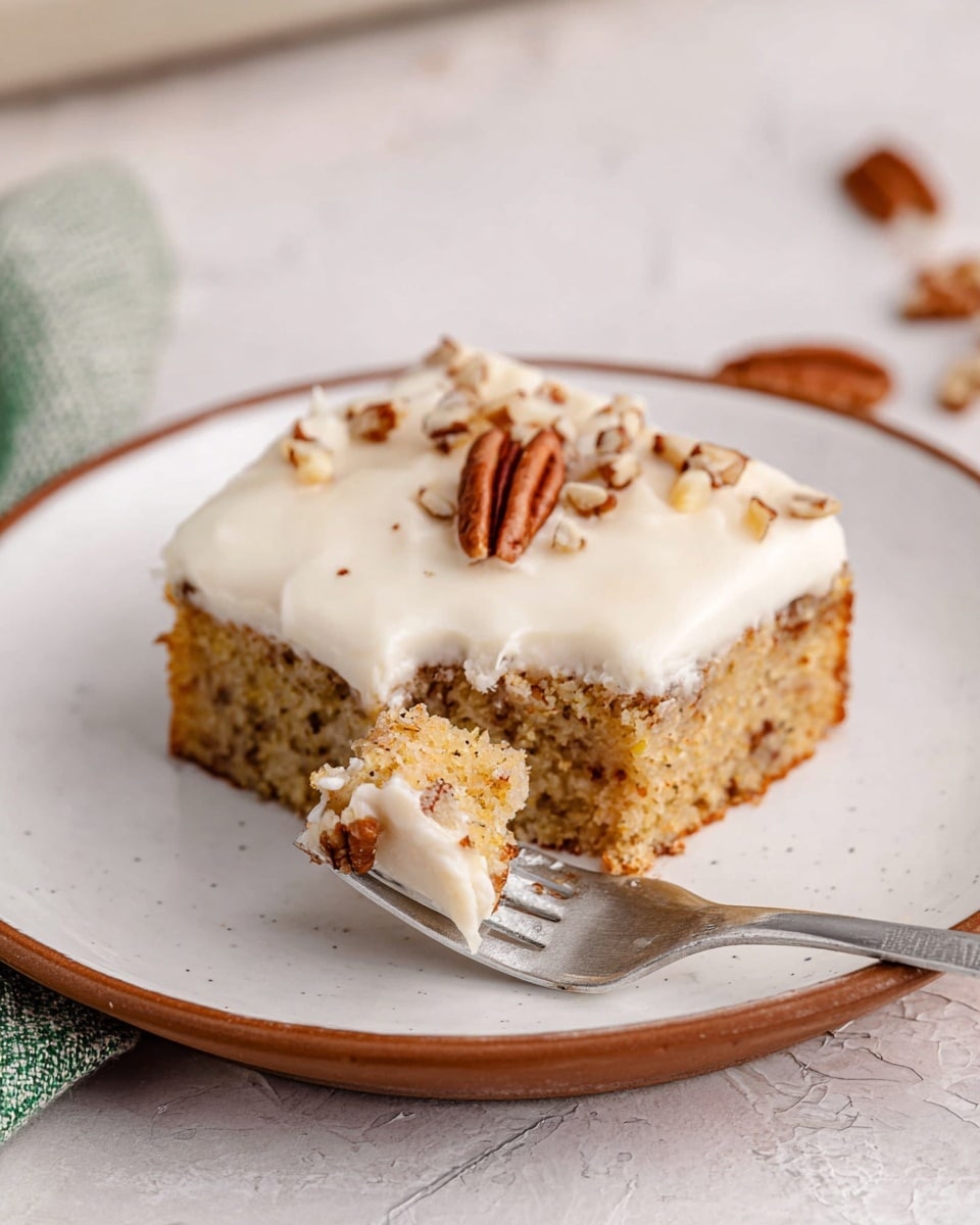 A square piece of cake sits on a white plate with a thin brown rim, placed on a white marbled texture. The cake has two layers: the bottom layer is a golden-brown moist cake with visible small specks, and the top layer is a smooth, thick white frosting spread evenly. Chopped pecans are sprinkled on top of the frosting. A silver fork rests on the plate with its tines partly inside the frosting, holding up a small portion of the cake. photo taken with an iphone --ar 4:5 --v 7