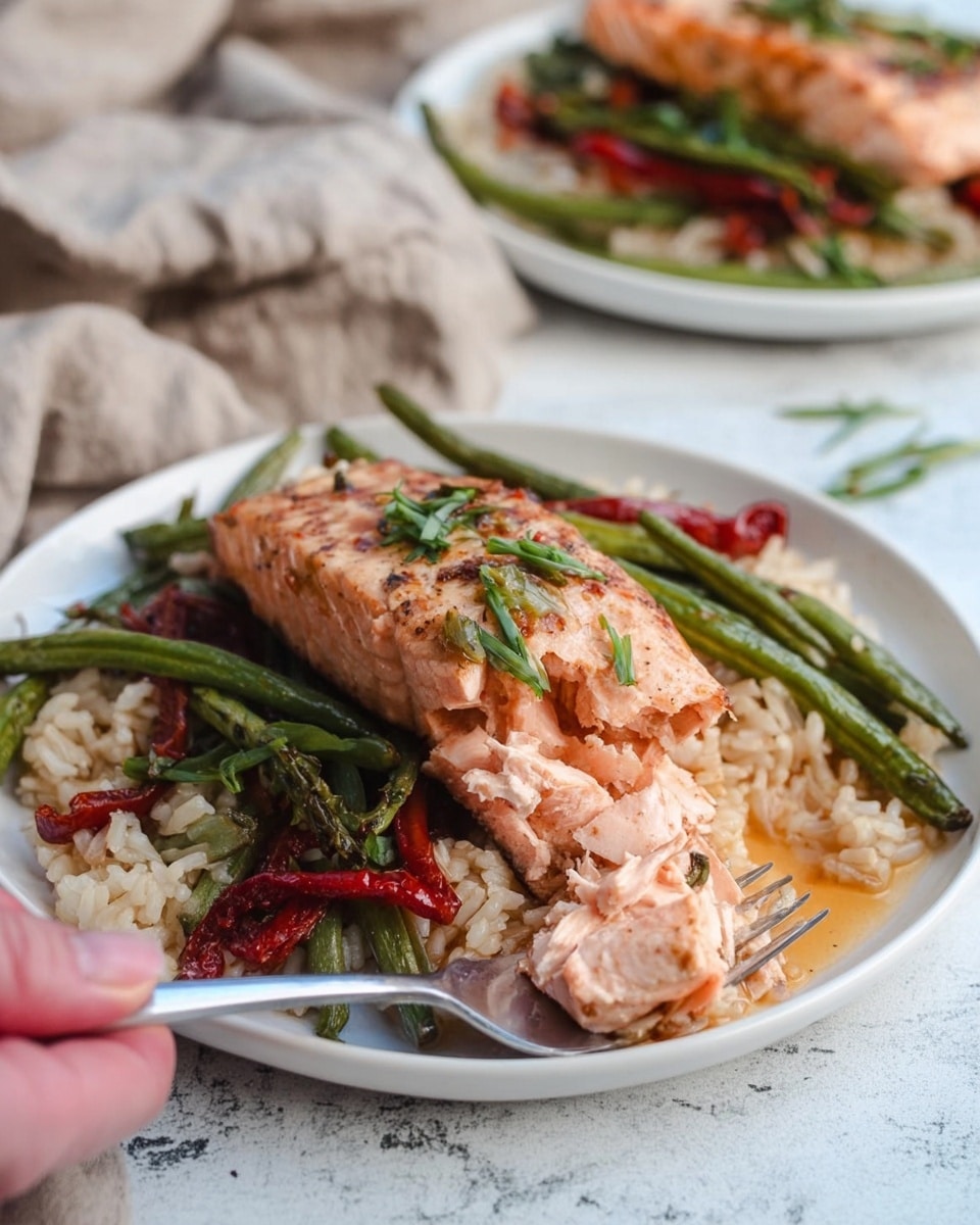 The dish shows a white plate on a white marbled surface, with three main layers. The bottom layer is light brown rice, with a slightly shiny texture. Above the rice, there are grilled green beans and red pepper strips scattered around, giving a mix of green and deep red colors. On top of everything is a piece of cooked salmon with a light brown seared crust and a soft pink inside, garnished with thin green herbs. A silver fork is placed in the rice and vegetables, and a woman's hand is gently holding a piece of the salmon, showing its soft texture. The background includes another similar plate with the same food out of focus. Photo taken with an iphone --ar 4:5 --v 7