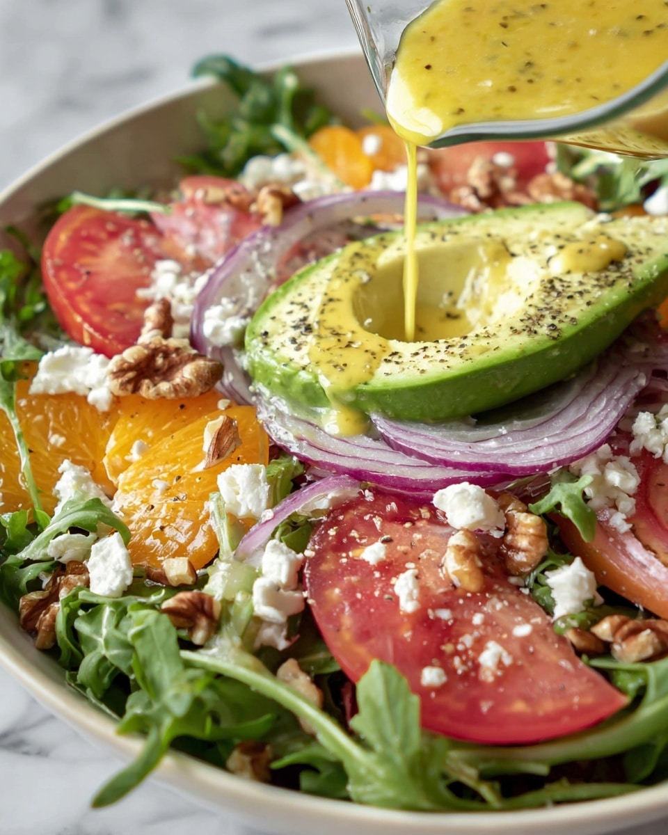 A close-up of a fresh salad in a white bowl with green arugula leaves as the base layer, topped with slices of red and orange tomatoes, scattered chopped walnuts, and crumbled white cheese. Thin rings of purple onion are spread over the salad. A halved avocado with a smooth light green inside is placed on the salad, sprinkled with black pepper. Yellow dressing with herbs is being poured over the salad from a small glass container above. The salad sits on a white marbled surface photo taken with an iphone --ar 4:5 --v 7