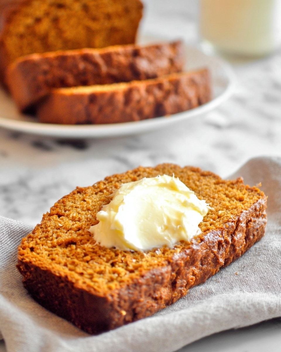 Two pieces of golden brown bread are stacked on a white marbled surface, with the top slice slightly tilted to reveal its soft and moist texture inside. The bread has a rough, crumbly crust with small holes and a dense, grainy interior that looks spongy and tender. In the background, part of a larger loaf with the same color and texture is visible but out of focus. photo taken with an iphone --ar 4:5 --v 7