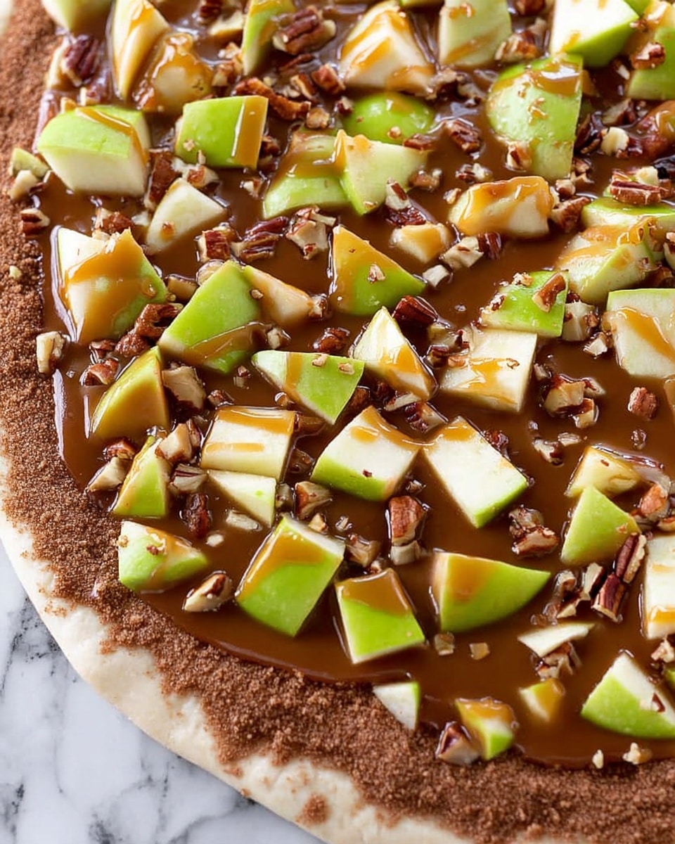 The image shows a close-up of a dessert pizza on a white marbled surface. The base is a light-colored dough crust with a visible edge, covered with a thick layer of crumbly brown cinnamon sugar. On top of that is a smooth, shiny caramel sauce spread in an even layer. Scattered over the caramel are many pieces of green apple, cut into various triangle and rectangular shapes with the skin still on, creating a fresh look. Small chunks of chopped pecans are sprinkled all over, adding texture and color contrast. The caramel sauce appears slightly glossy and drizzled in places over the apples and nuts. Photo taken with an iphone --ar 4:5 --v 7