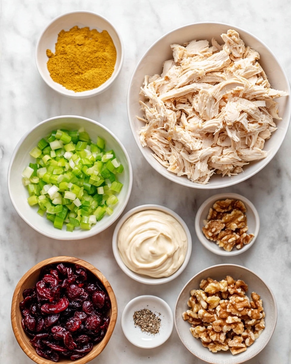 A top view of several white bowls arranged on a white marbled surface, with a large white bowl filled with shredded cooked chicken in the top right. Surrounding it are smaller white bowls holding bright yellow turmeric powder, chopped celery in pale green, creamy white mayonnaise swirled smoothly, chopped green onions in fresh light green, and crushed walnuts in tan and brown shades. There is a small white plate with ground black pepper near the chicken, and a wooden bowl filled with dark red dried cranberries completes the layout. The image is bright and clean with a focus on the natural colors and textures of each ingredient, photo taken with an iphone --ar 4:5 --v 7
