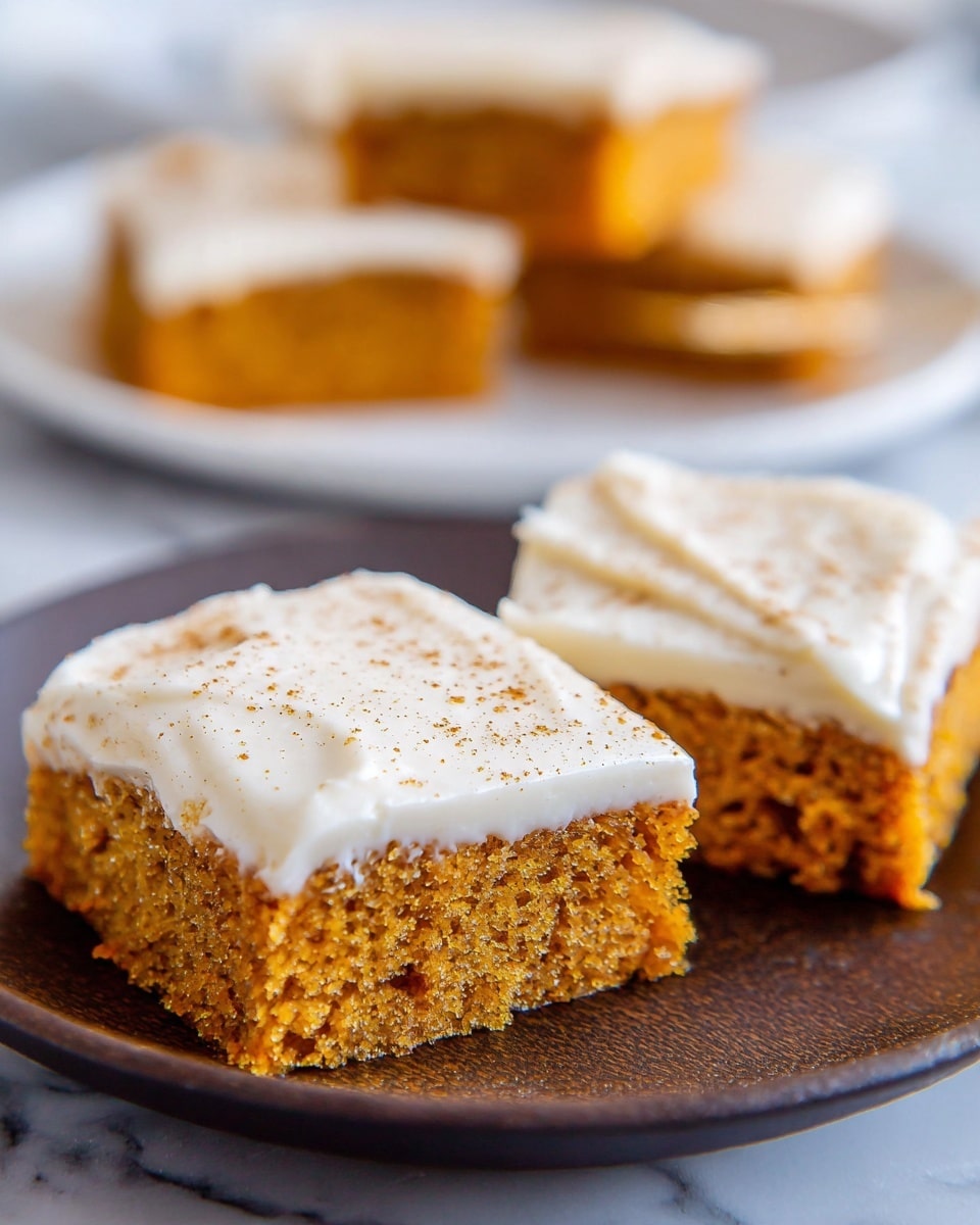 Two square pieces of cake with one piece overlapping the other are on a white plate. Each cake piece has two layers: the bottom layer is a soft, moist, orange-brown cake with a crumbly texture, while the top layer is a smooth, white frosting sprinkled with light brown spices. A blurred white plate in the background holds two more square cake pieces. The setting is on a white marbled surface. Photo taken with an iphone --ar 4:5 --v 7